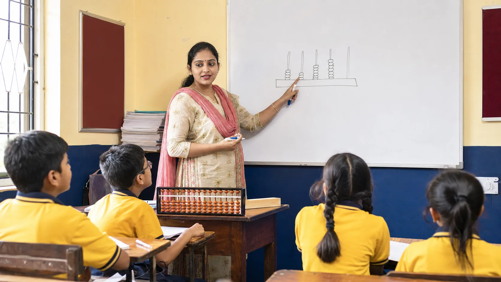 Teacher explaining abacus place value at classroom board